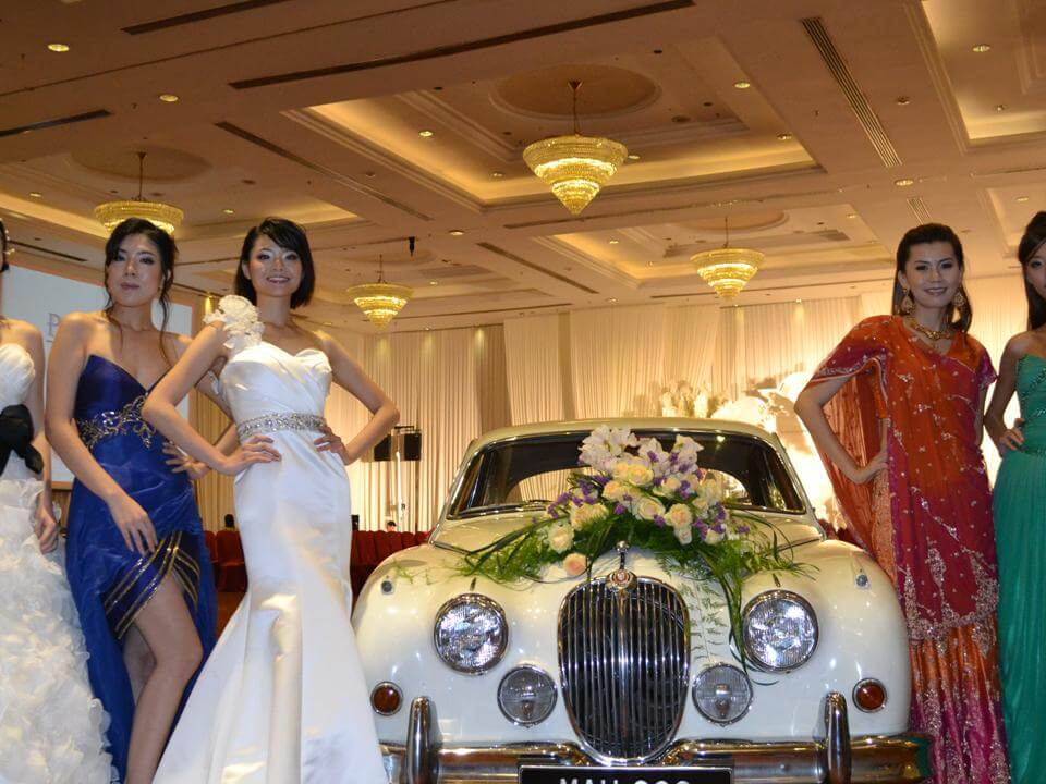Models posing for a photography session on a classic car