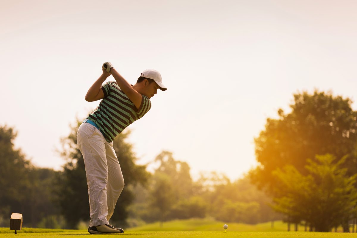 Golfers are going to hit a golf ball. On the golf course during the summer