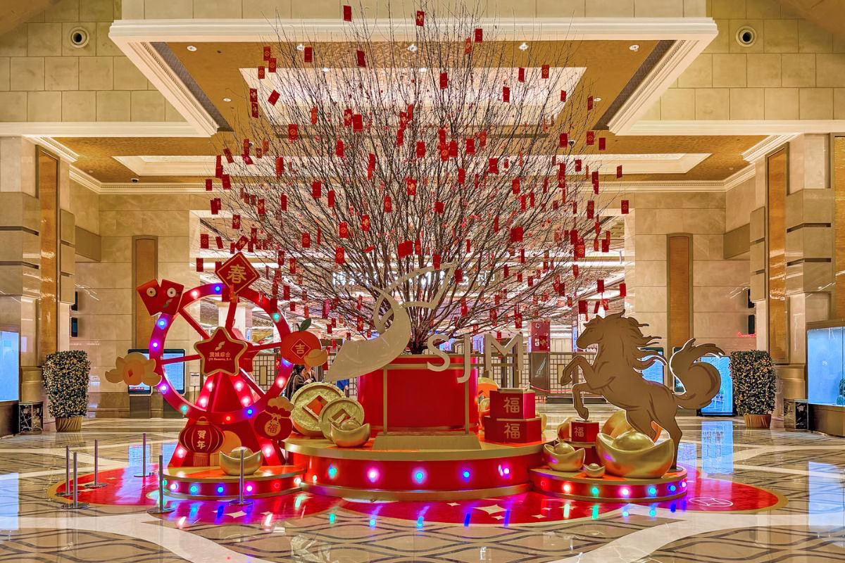 A towering peach blossom tree takes centre stage, flanked by majestic golden horses and oversized ingots, offering a grand, auspicious welcome that immediately immerses guests in the celebratory spirit.