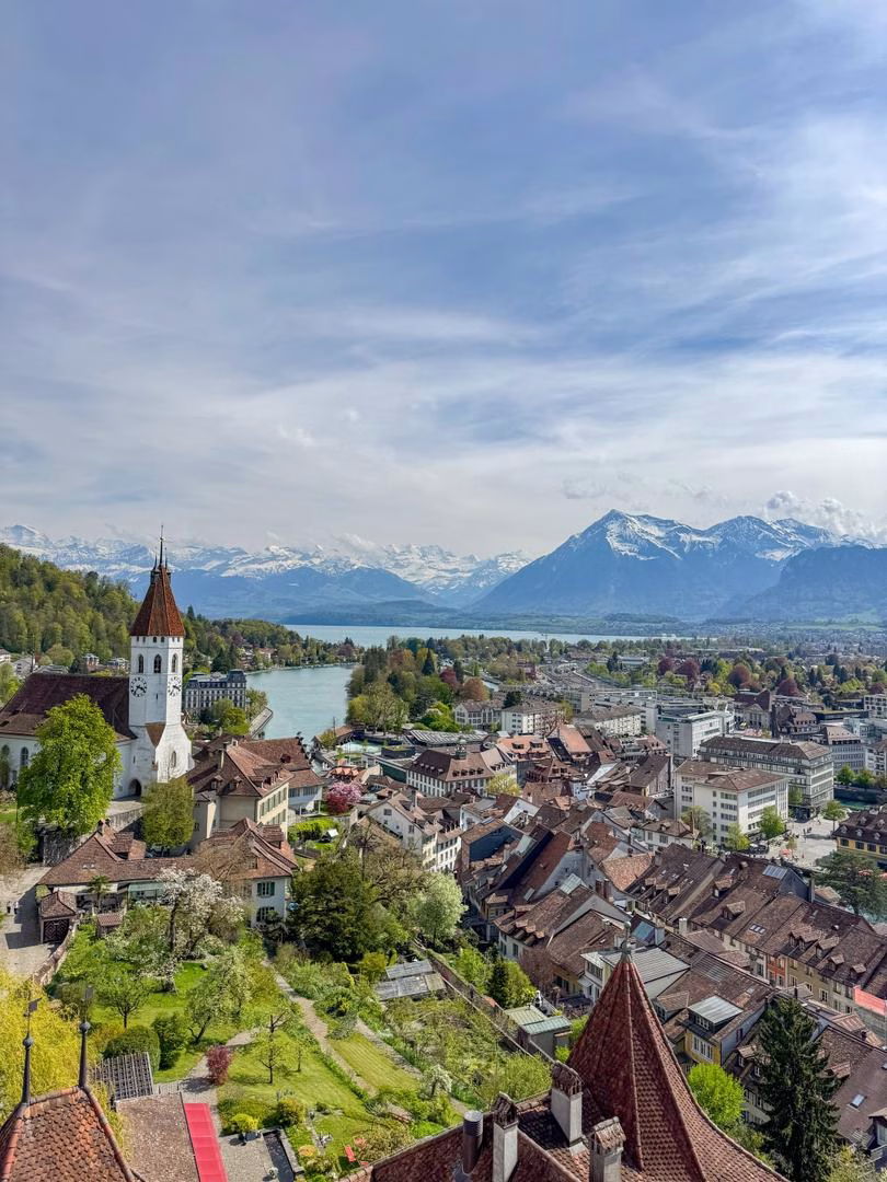 Panoramic view from Schloss Thun overlooking Thun's historic old town, the Aare River, Lake Thun and the Swiss Alps.