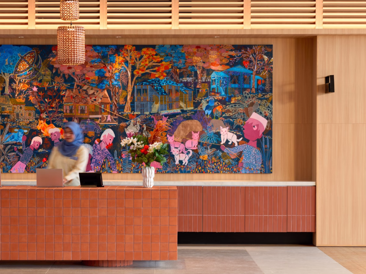 Reception counter at ASAI Gamuda Cove featuring terracotta tiles, warm wood finishes and colourful artwork by Malaysian artist Tan Ken Ming.