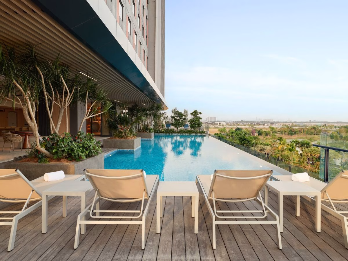 The infinity pool at ASAI Gamuda Cove features sun loungers, tropical landscaping and views of the surrounding greenery in Selangor, Malaysia.