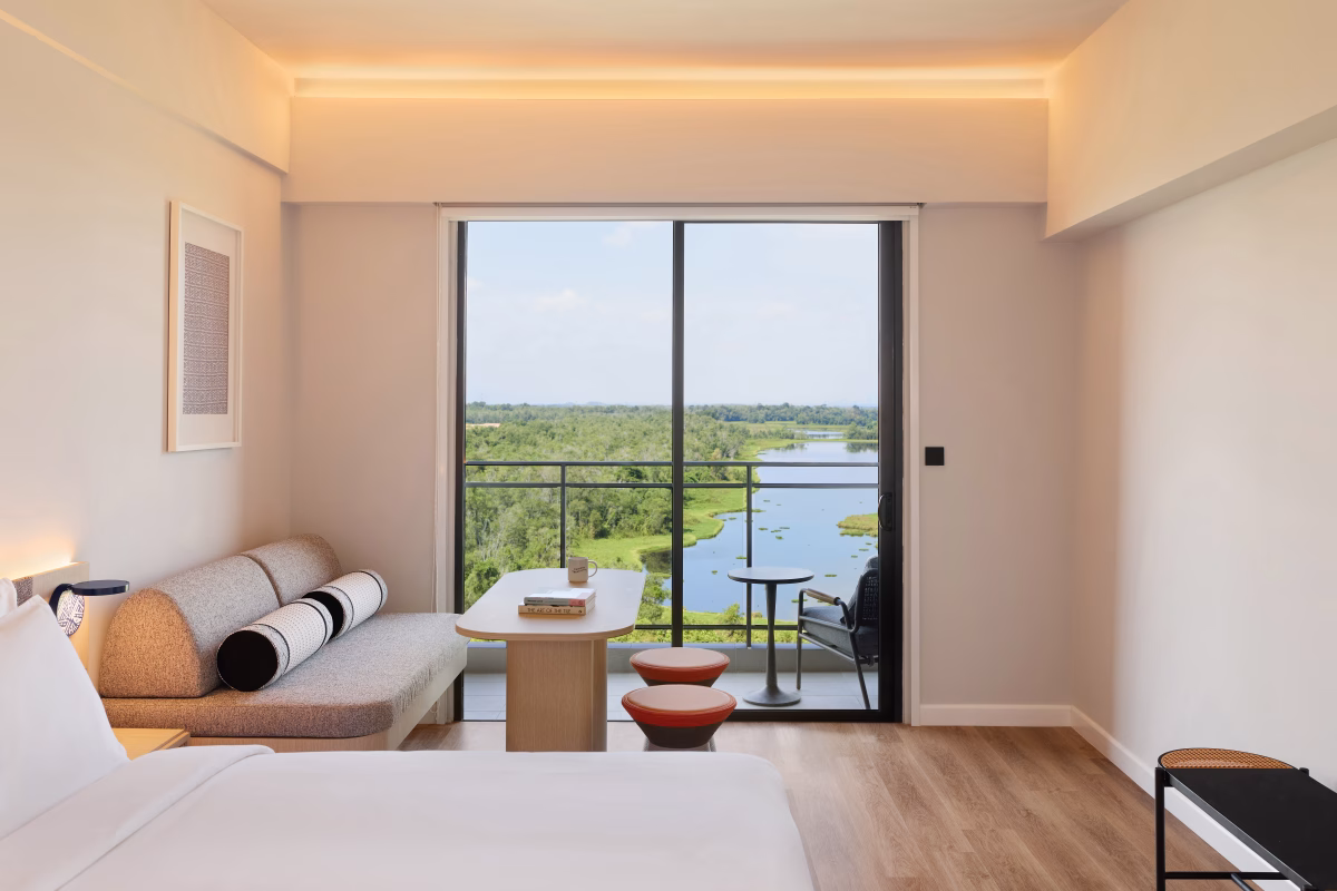 Roomy Balcony King Room at ASAI Gamuda Cove featuring a king-sized bed, sofa seating and a private balcony overlooking the wetlands.