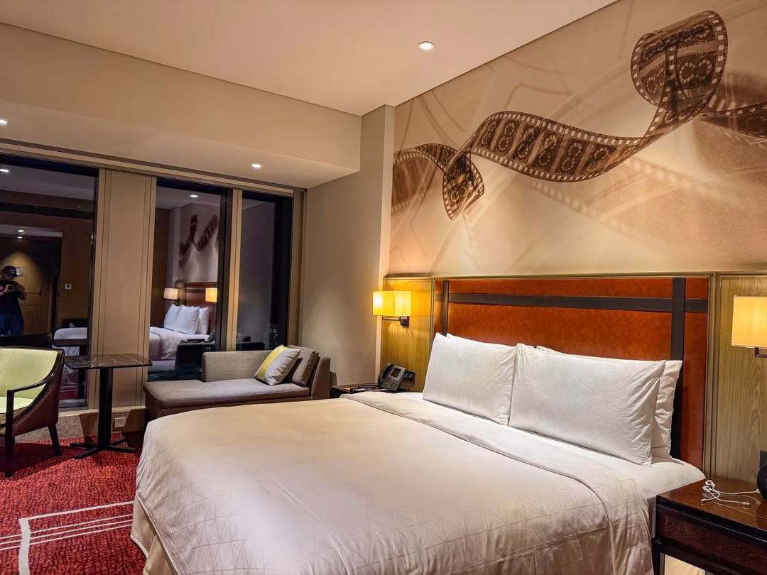 King bed, film-reel wall art and contemporary furnishings inside a Celebrity Premium Vista Room at Studio City Macau.