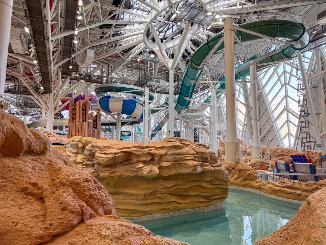 Indoor water park at Studio City Macau featuring colourful water slides, a turquoise pool and artificial rock formations.